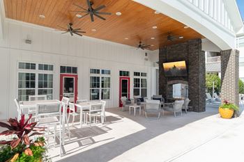 A patio with a white table and chairs and a ceiling fan.